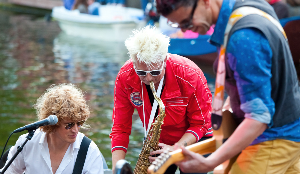 Muzikanten spelen gitaar en saxofoon op een boot tijdens optreden Muzikanten spelen gitaar en saxofoon op een boot tijdens optreden